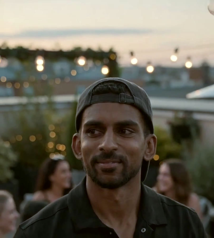 AI-generated image of Gin smiling among friends on a rooftop at dusk