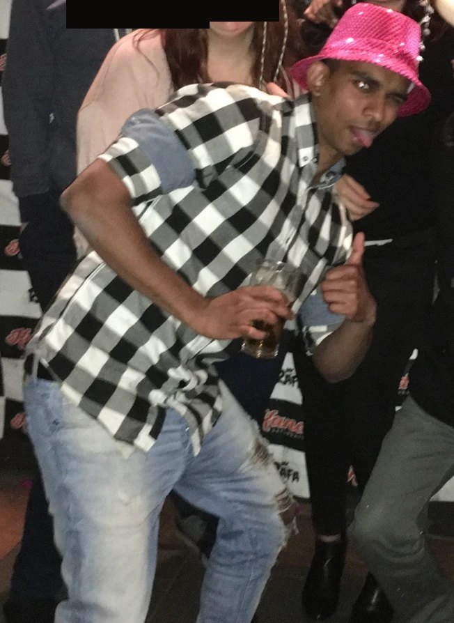 Gin in a pink party hat holding a drink, other faces blurred