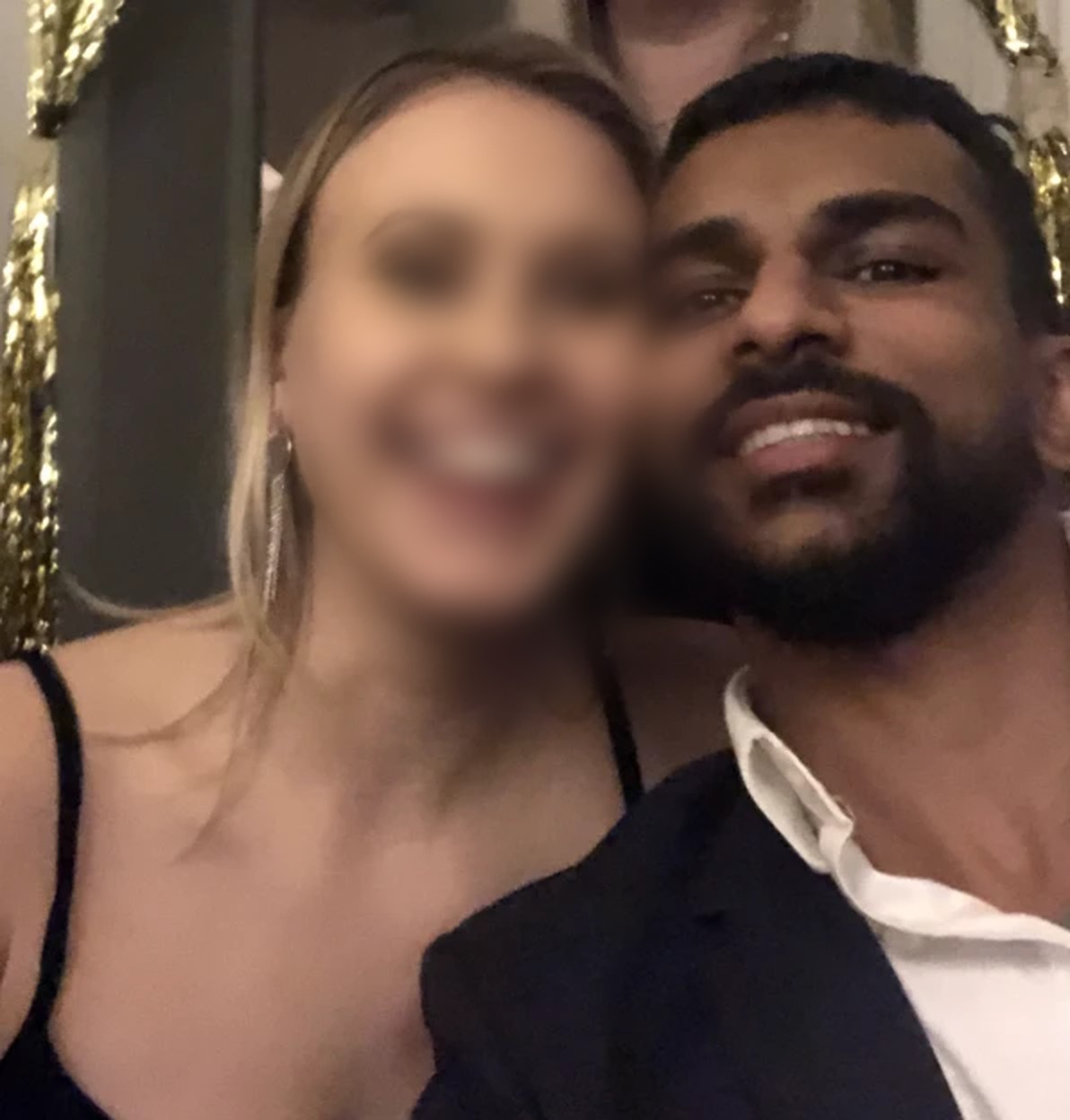 Gin smiling cheek to cheek with a woman, her face blurred