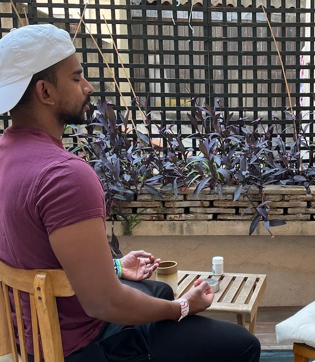 Gin meditating with his eyes closed on a sunny terrace