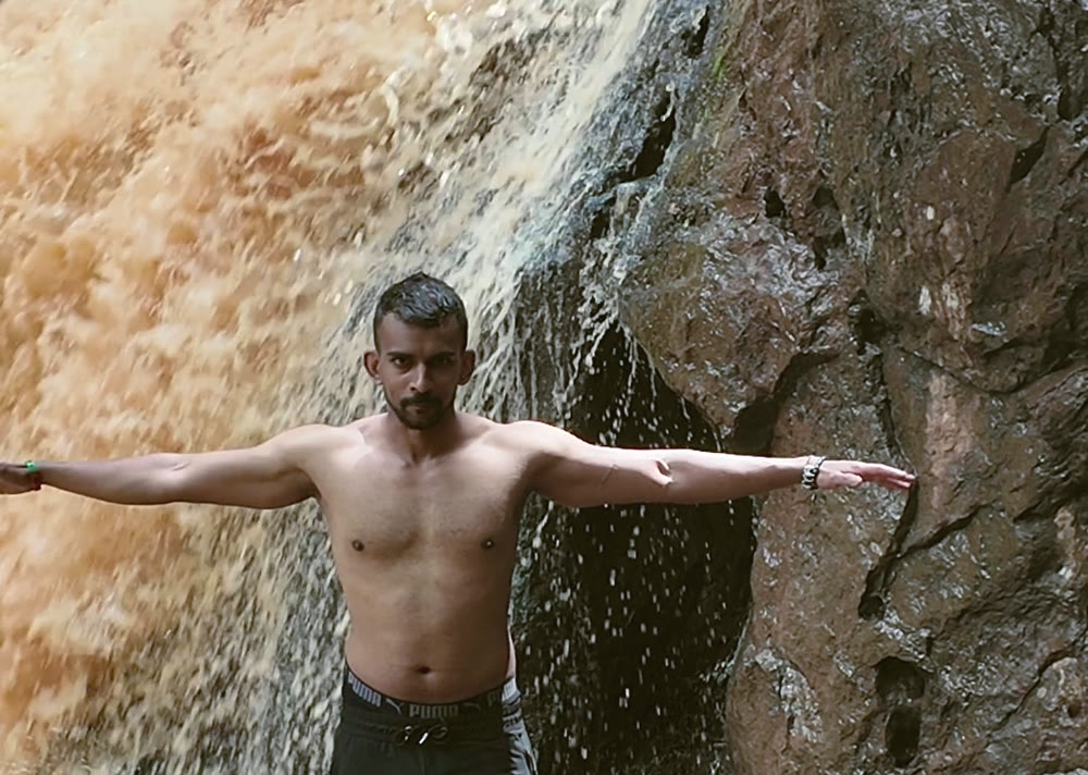 Gin with arms wide in front of a waterfall